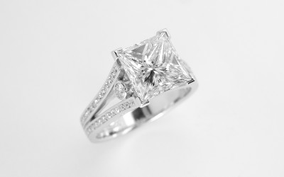 A 2.01ct. 'G' colour Princess cut diamond mounted in a split shoulder platinum ring mount with small round brilliant cut diamonds channel set in shoulders. Ideal diamond size 1.5ct to 5ct