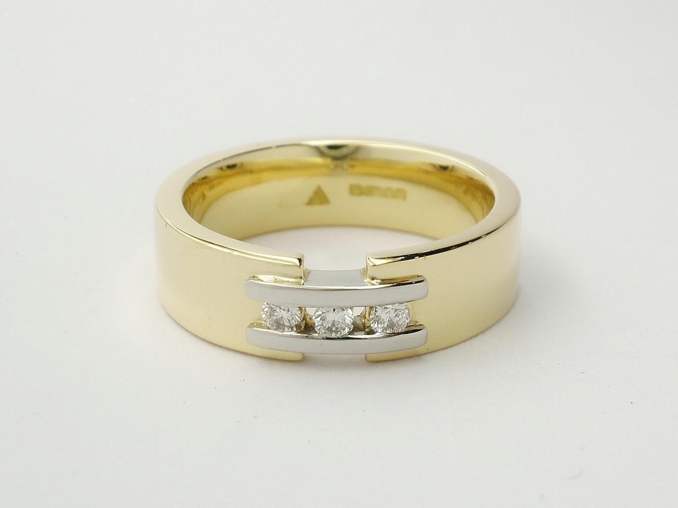 Ladies' 18ct. yellow gold wedding ring with a pair of platinum 'tram line' wires inlayed & bridging a gap across the top, set with 3 round brilliant cut diamonds.