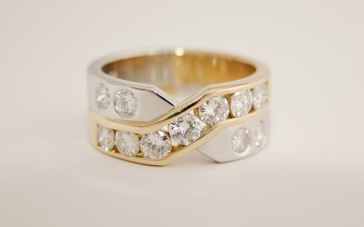 Platinum & 18ct. yellow gold 11 stone channel and flush set diamond cross over style ring.