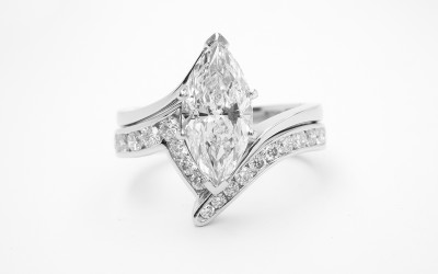 Platinum zig-zag wedding ring shaped to fit around a single stone marquise cross-over engagement ring and channel set with round brilliant cut diamonds to 55% cover.