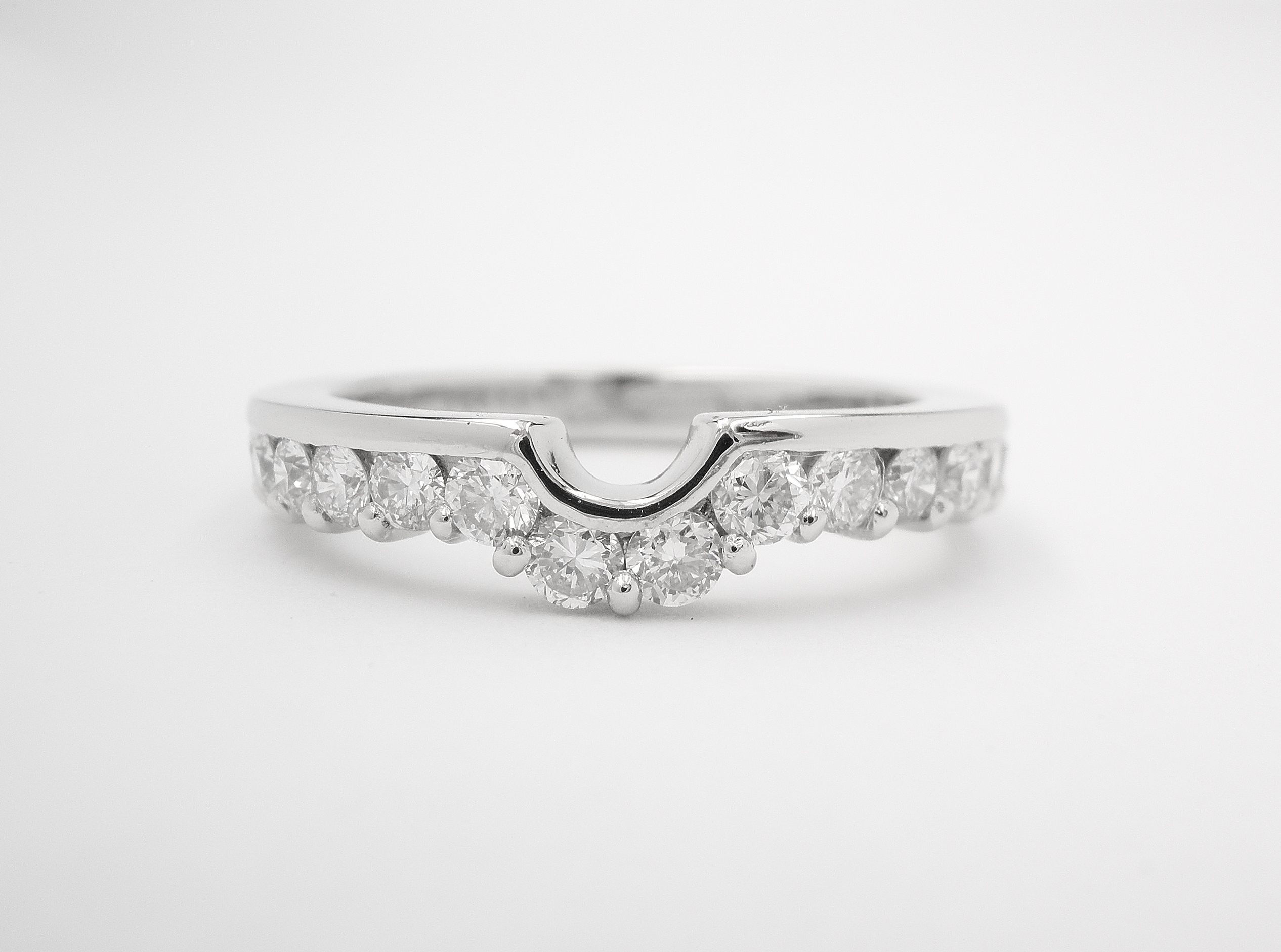 Part channel set platinum wedding ring shaped to fit with a single stone round diamond engagement ring.