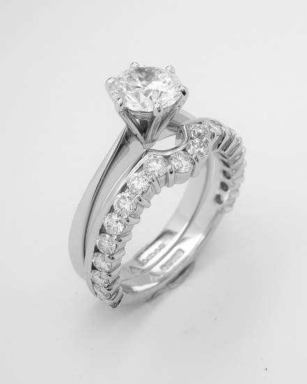 Part channel set platinum wedding ring shaped to fit with a single stone round diamond engagement ring.