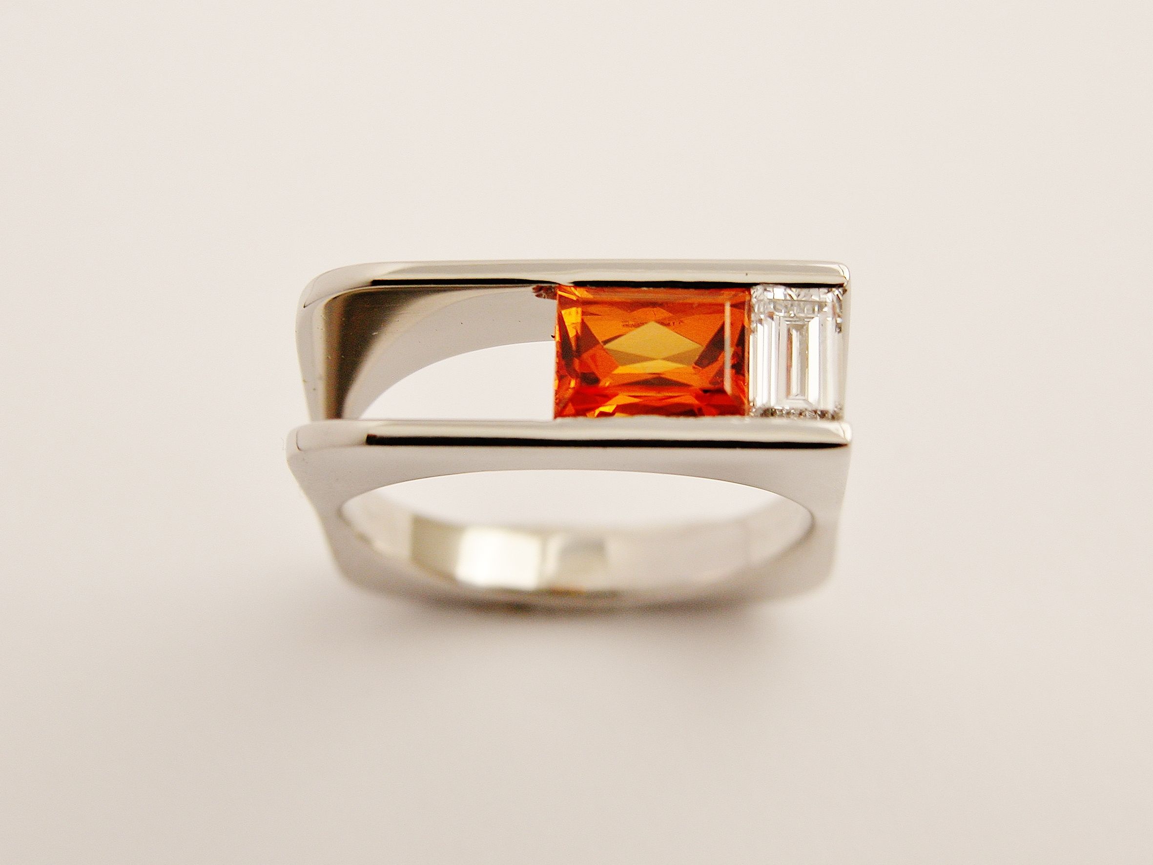 Orange sapphire baguette & baguette cut diamond channel set in a plateau, square sectioned, palladium ring.