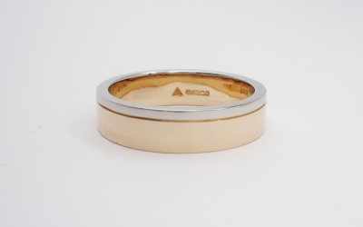 9ct. Red gold (also known as rose gold or pink gold) gents wedding ring with broad palladium wire applied on one edge.