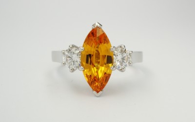 Orange marquise sapphire & round brilliant cut diamond 3 stone ring, mounted in platinum & palladium with diamond set shoulders.