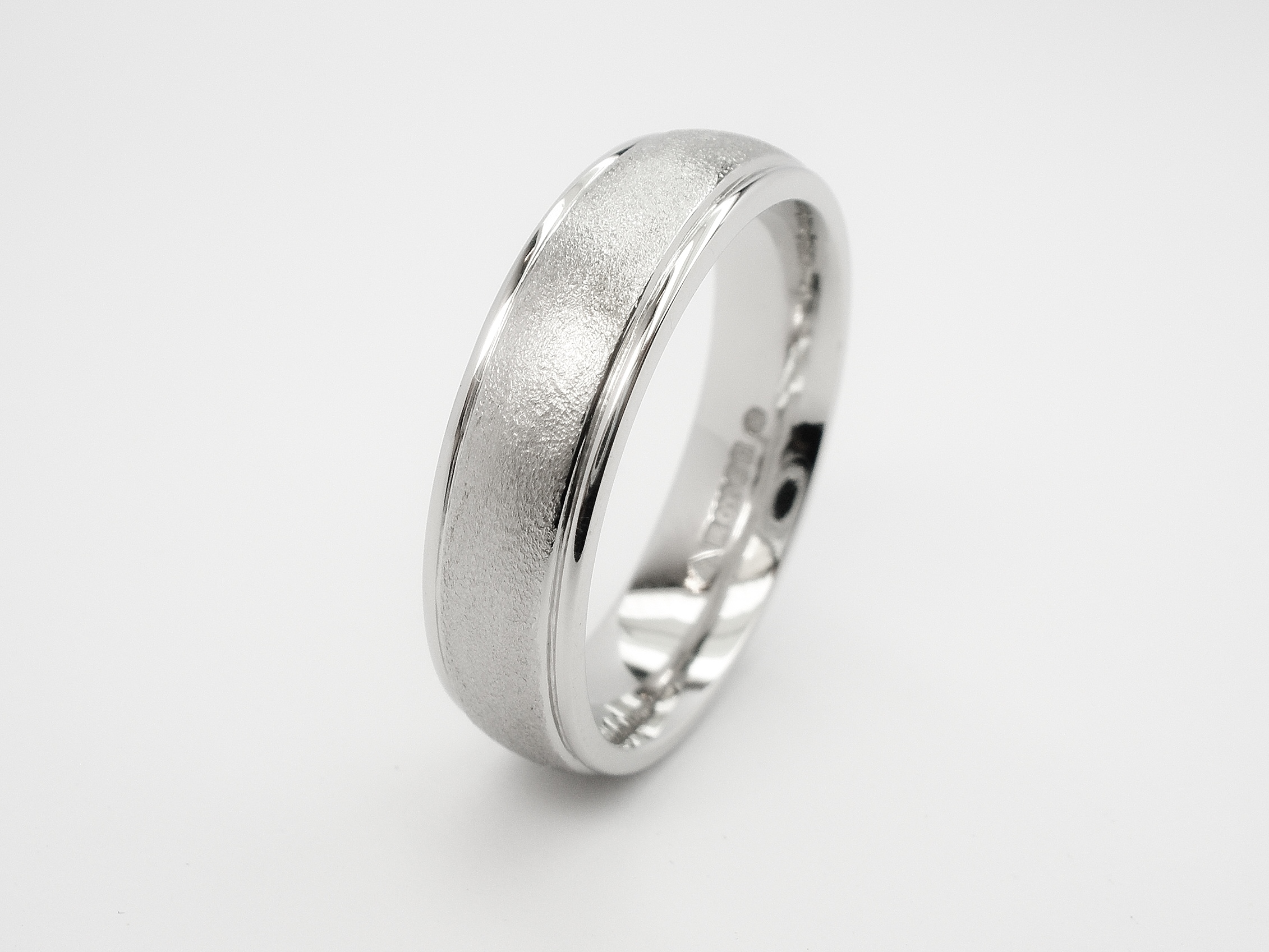 Gents platinum court sectioned wedding ring with a stipple finished centre and polished tram lines on edges.