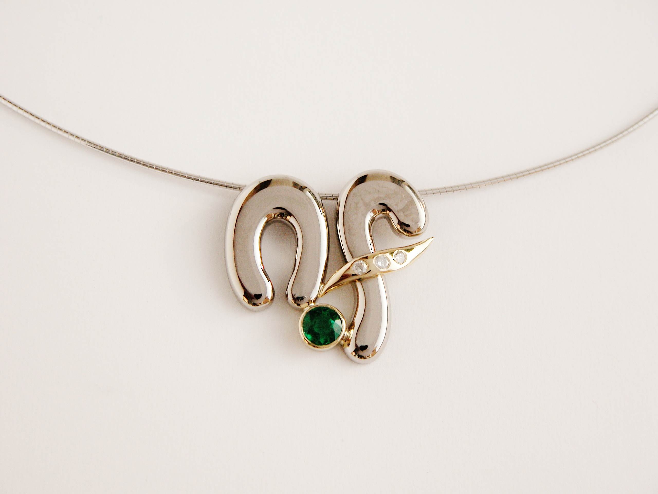 Round emeralds rub-over set in initial style 18ct. white & yellow gold pendant with small round brilliant cut diamonds flush set in the 18ct. yellow gold.