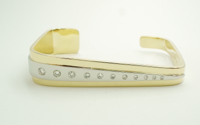 18ct yellow gold and palladium tapered rectangular torque bangle flush set with tapering round brilliant cut diamonds.