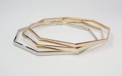 A treo of octagonal bangles one each created from palladium, 9ct. yellow gold & 9ct. red gold (also known as 9ct. rose gold or 9ct. pink gold).