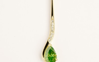 Olive coloured Pear shaped diamond and round brilliant cut white diamond hook shaped pendulum style pendant mounted in 18ct. yellow gold.