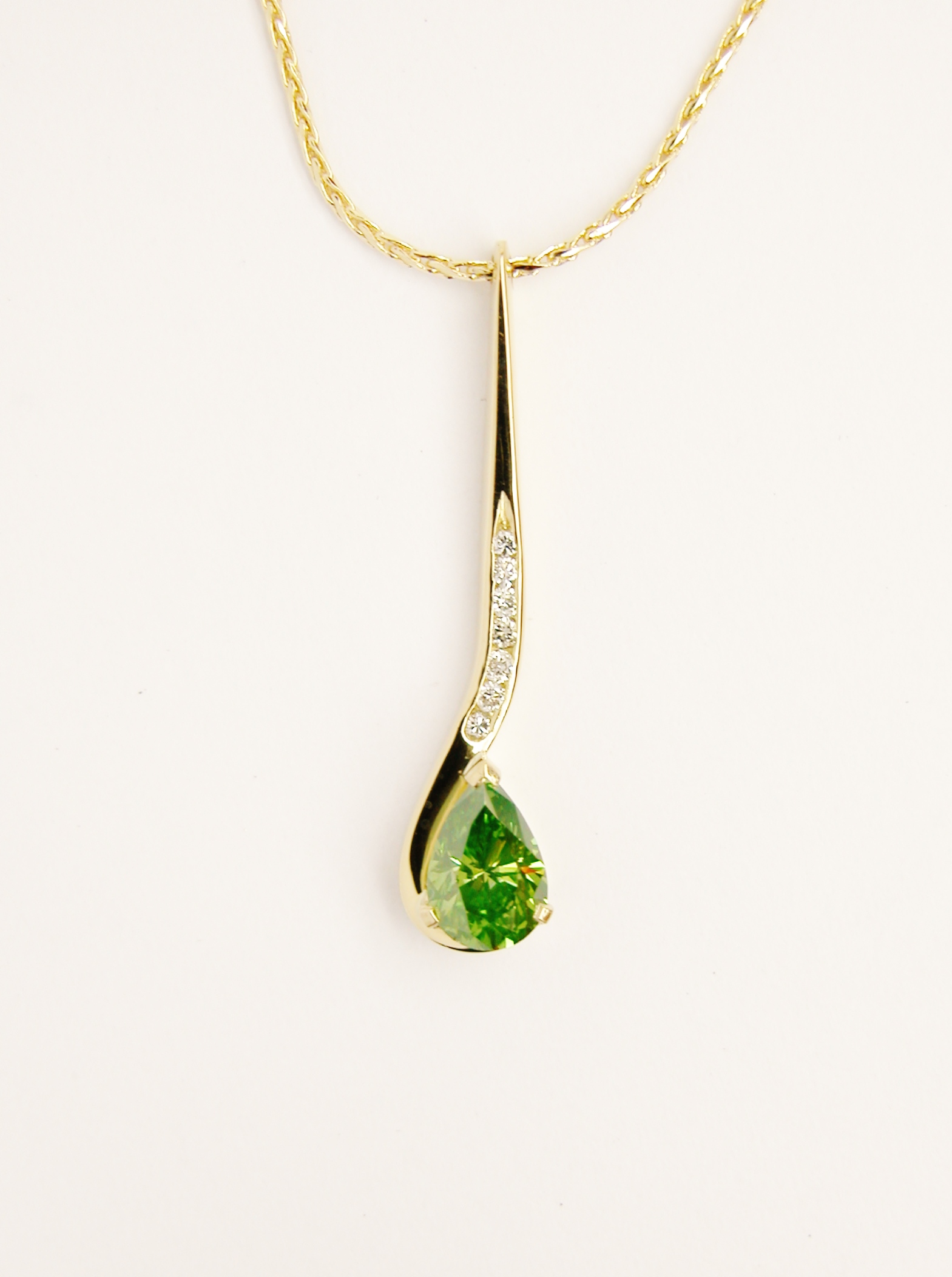 Olive coloured Pear shaped diamond and round brilliant cut white diamond hook shaped pendulum style pendant mounted in 18ct. yellow gold.