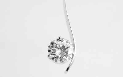 Single stone round brilliant cut diamond 'S' shaped fine platinum wire pendant.