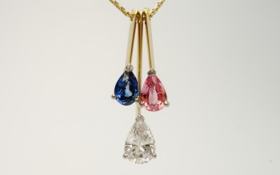 Tear drop shaped diamond,tear drop shaped pink sapphire & tear drop shaped blue sapphire triple 18ct. yellow gold pendulum style pendant.