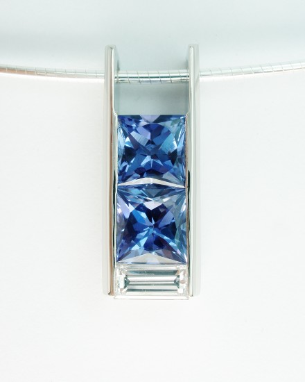 Tanzanite square cut matching pair with diamond baguette set in a box style 18ct. white gold pendant.