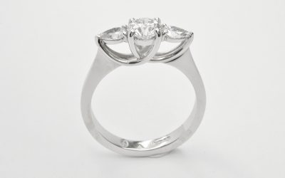 A 3 stone round brilliant cut and pear shaped diamond 'cradle' set ring mounted in platinum.