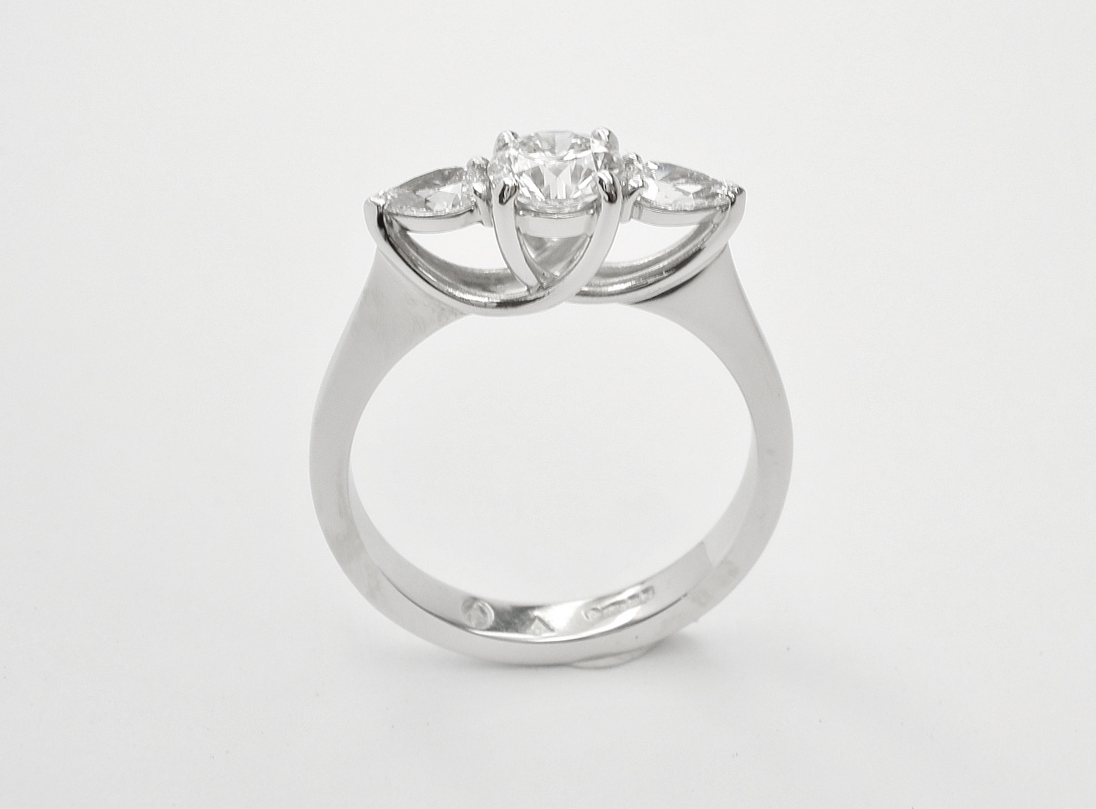 A 3 stone round brilliant cut and pear shaped diamond 'cradle' set ring mounted in platinum.