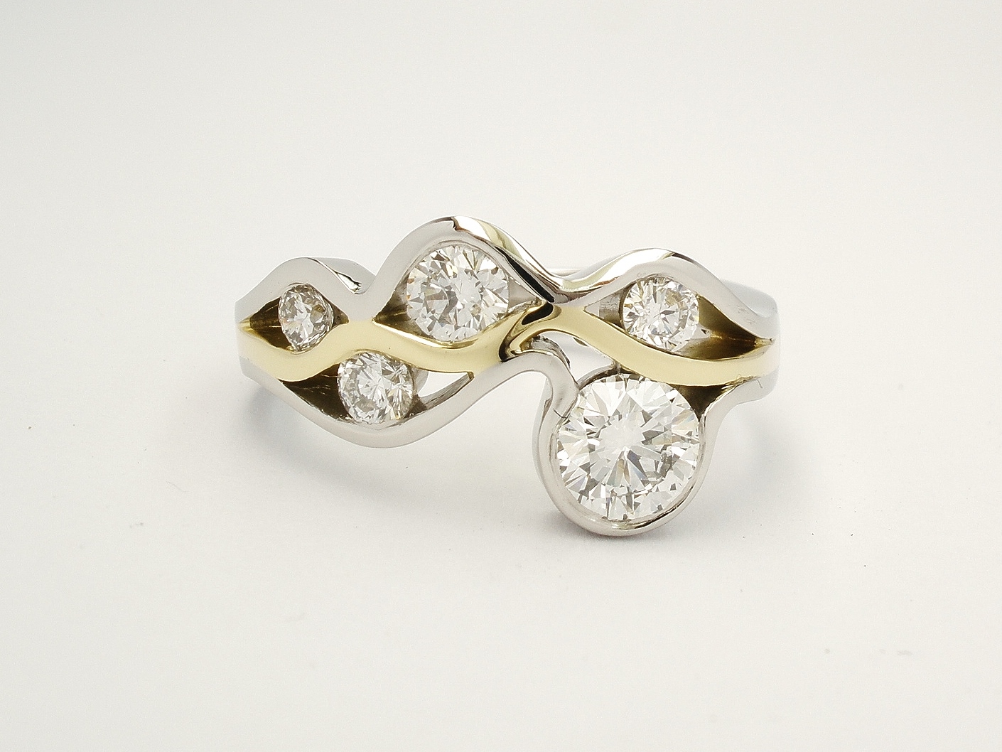 Round brilliant cut diamond 'Wave' ring mounted in Platinum and 18ct. yellow gold.