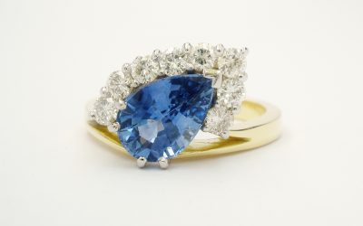 Pear shaped sapphire and round brilliant cut diamond part offset cluster ring mounted in 18ct. yellow gold and platinum.