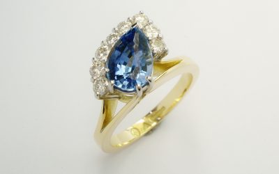 Pear shaped sapphire and round brilliant cut diamond part offset cluster ring mounted in 18ct. yellow gold and platinum.