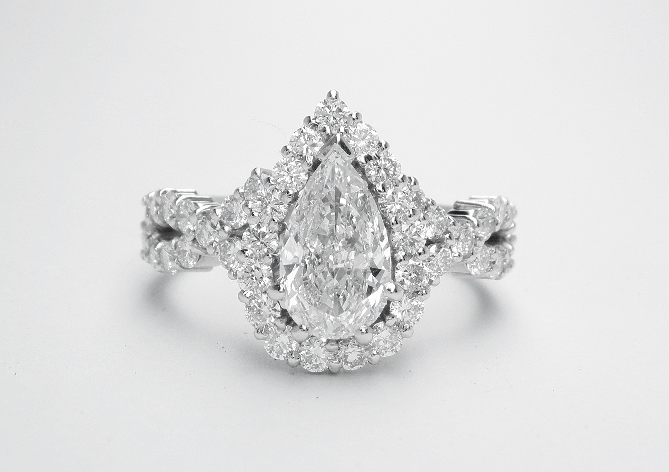 Pear shaped halo cluster ring with centre 0.70ct. 'D'colour pear diamond & criss-cross diamond shoulders set in platinum.