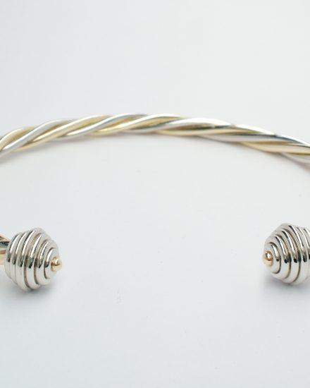 9ct. yellow gold and palladium 2 tone twisted rope style torque bangle with palladium ringed spherical ends.