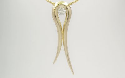 A single round brilliant cut diamond set in an 18ct. yellow gold tapered loop pendant.