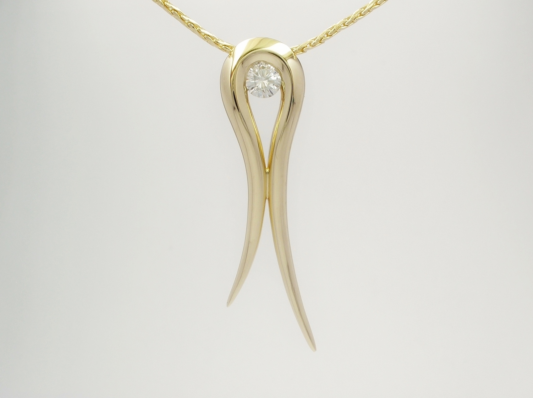 A single round brilliant cut diamond set in an 18ct. yellow gold tapered loop pendant.