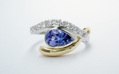 A 12 stone pear shaped tanzanite and round brilliant cut diamond open cross-over ring mounted in platinum & 18ct. yellow gold.
