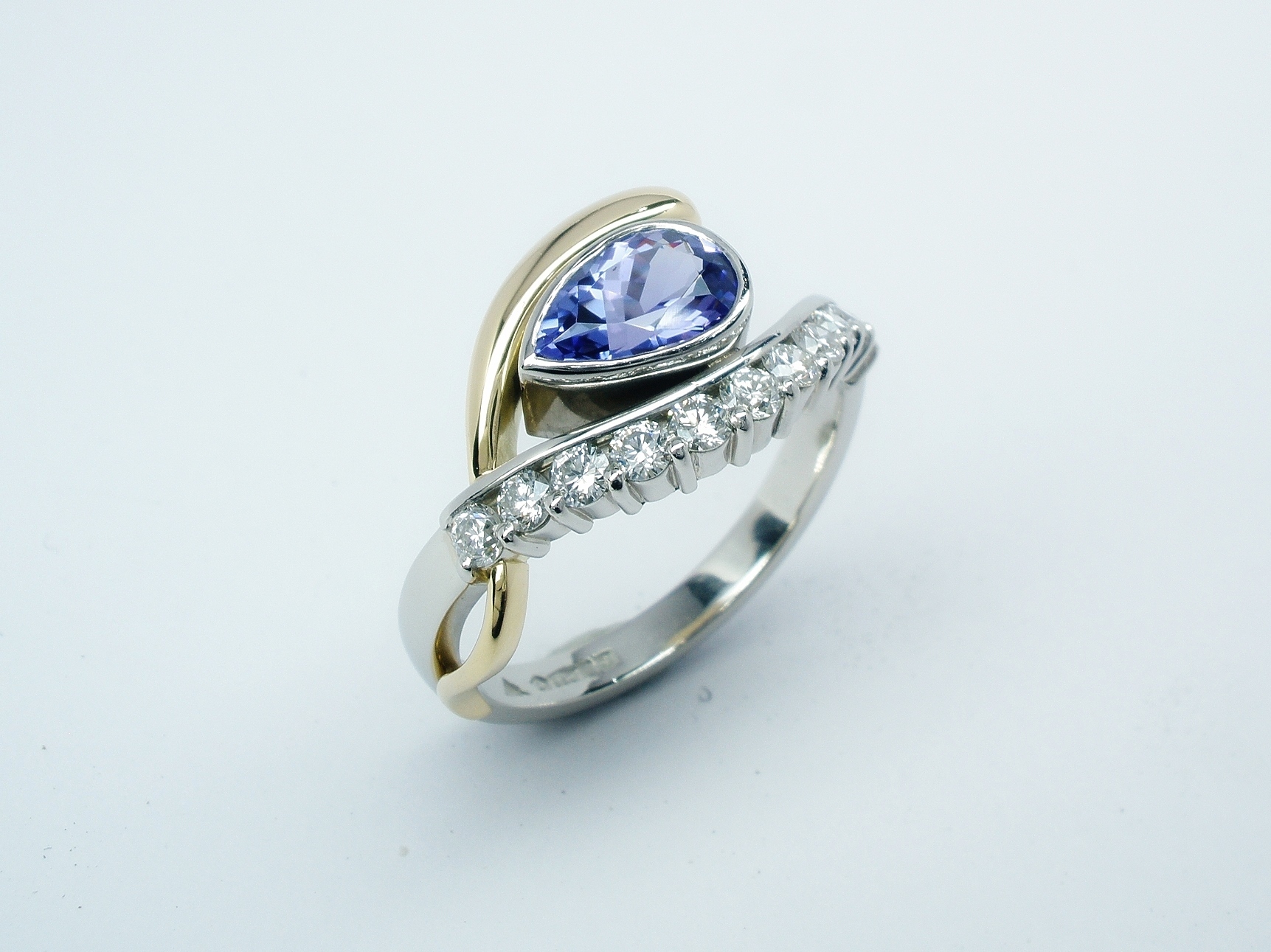 A 12 stone pear shaped tanzanite and round brilliant cut diamond open cross-over ring mounted in platinum & 18ct. yellow gold.