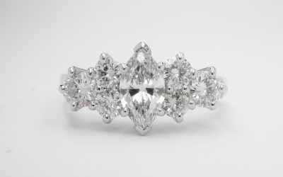 A central marquise diamond flanked on either side with a trefoil of round brilliant cut diamond creating a 7 stone ring mounted in platinum.