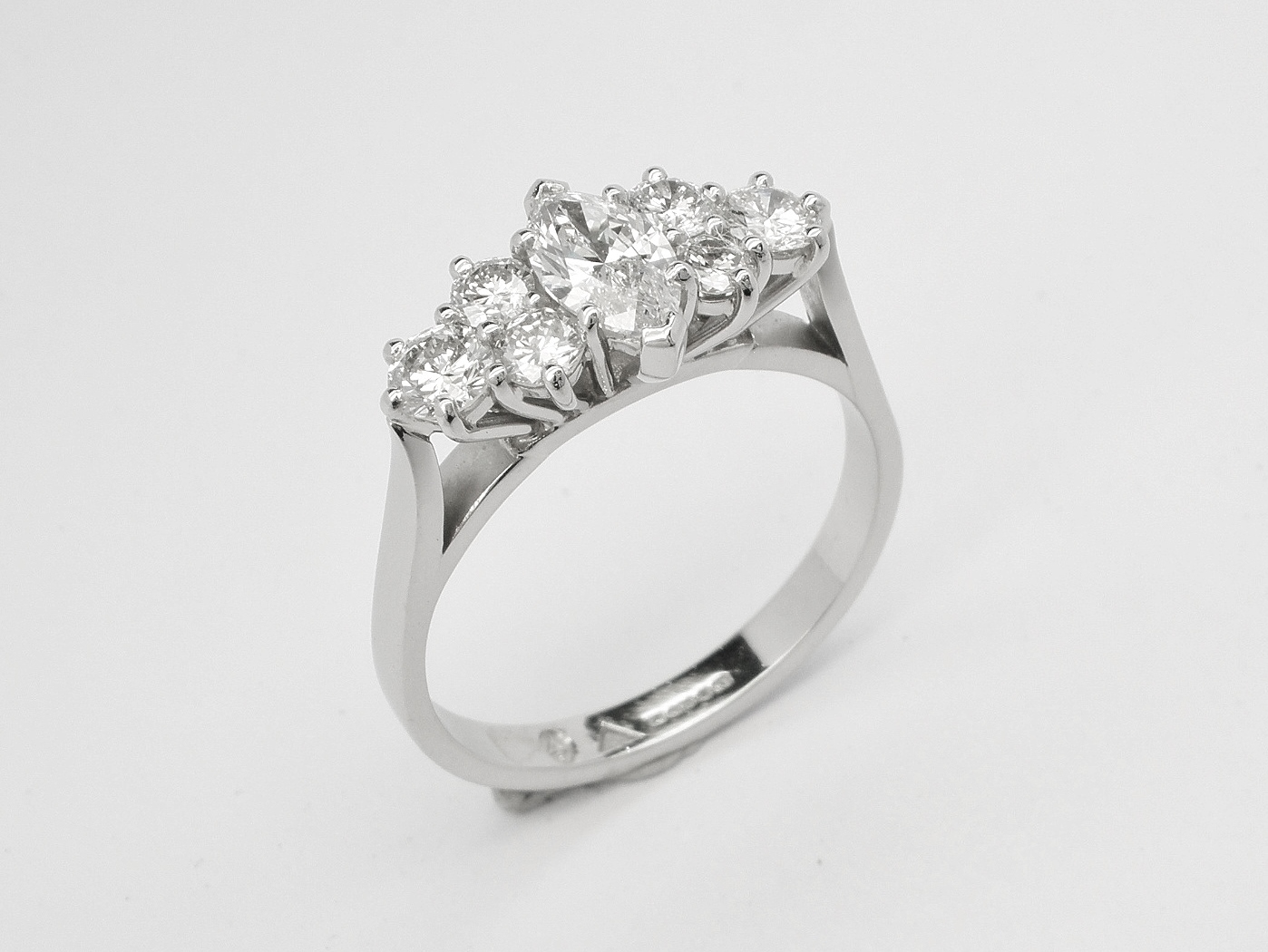 A central marquise diamond flanked on either side with a trefoil of round brilliant cut diamond creating a 7 stone ring mounted in platinum.