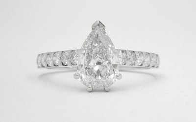 A single pear shaped diamond ring mounted in platinum with round brilliant cut diamonds cut down set in the shoulders.