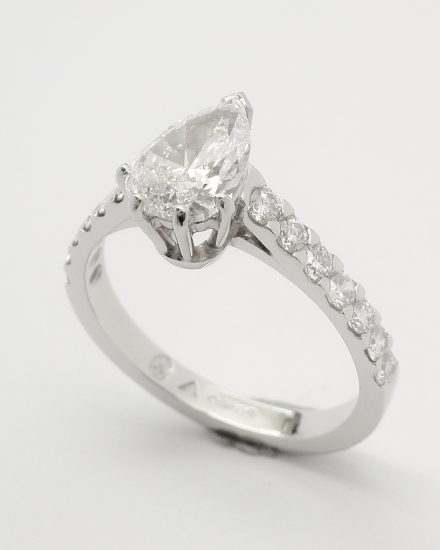 A single pear shaped diamond ring mounted in platinum with round brilliant cut diamonds cut down set in the shoulders.