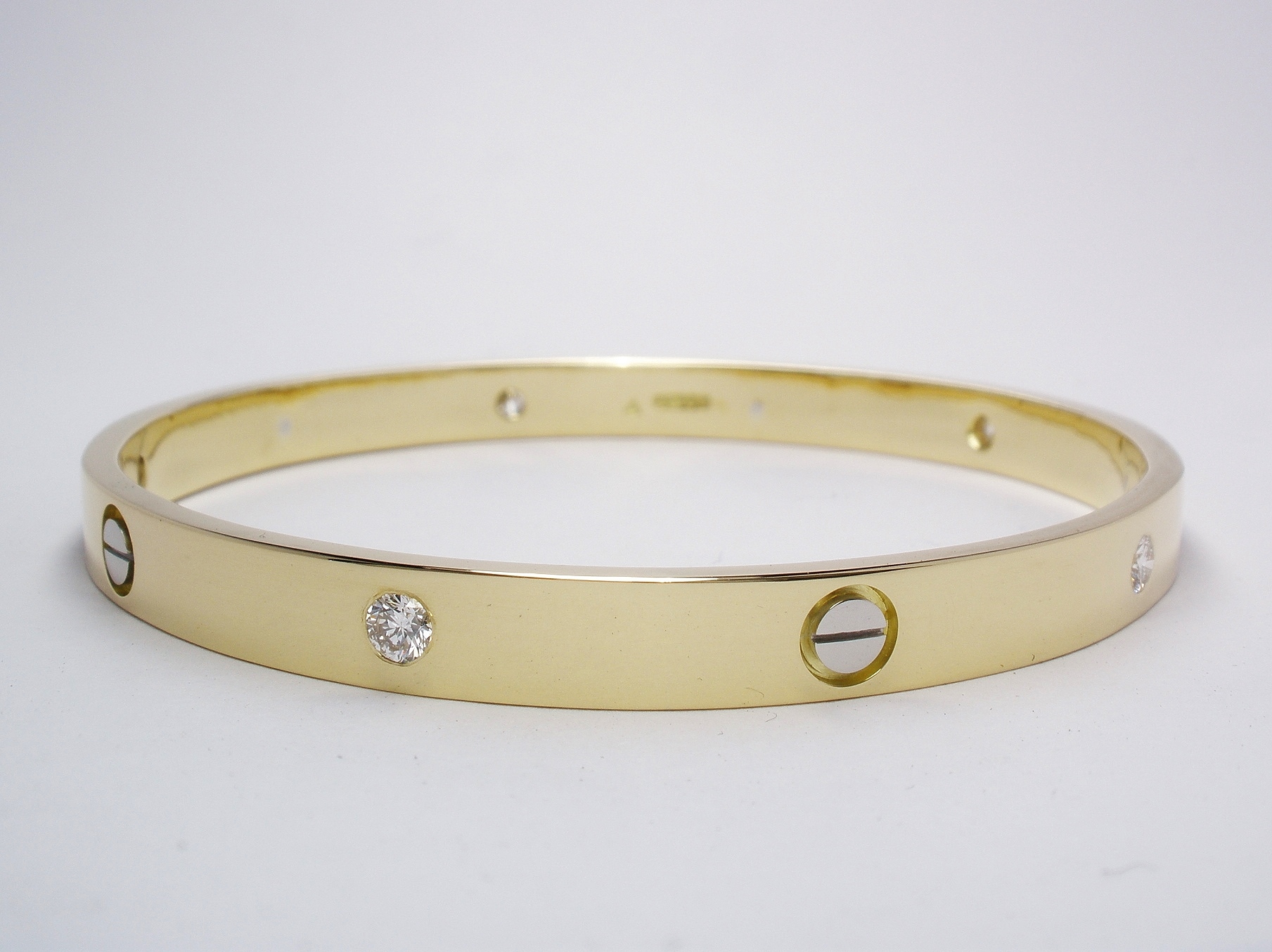 18ct. yellow gold solid bangle with 5 round brilliant cut diamonds flush set and 5 platinum screw heads inlayed.