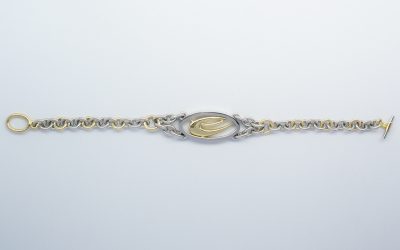 A palladium & 18ct. yellow gold bracelet with central oval panel and 18ct. yellow gold stylised initial.