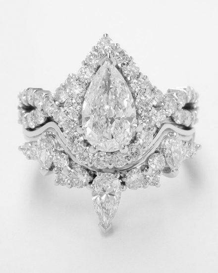 A pear and brilliant cut diamond wedding ring shaped to fit around a pear shaped 'halo' cluster engagement ring with criss-cross diamond shoulders.