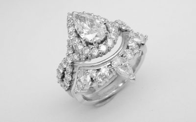 A pear and brilliant cut diamond wedding ring shaped to fit around a pear shaped 'halo' cluster engagement ring with criss-cross diamond shoulders.