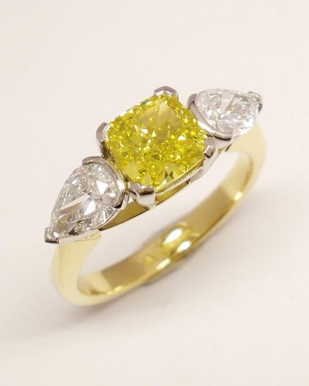 A 1.50ct. Canary yellow, square cushion cut diamond and 'D' coloured white pear shaped diamonds mounted as a 3 stone ring in 18ct. yellow gold and platinum.