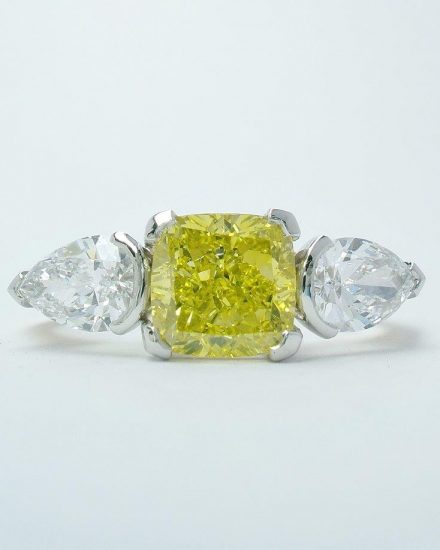 A 1.50ct. Canary yellow, square cushion cut diamond and 'D' coloured white pear shaped diamonds mounted as a 3 stone ring in 18ct. yellow gold and platinum.