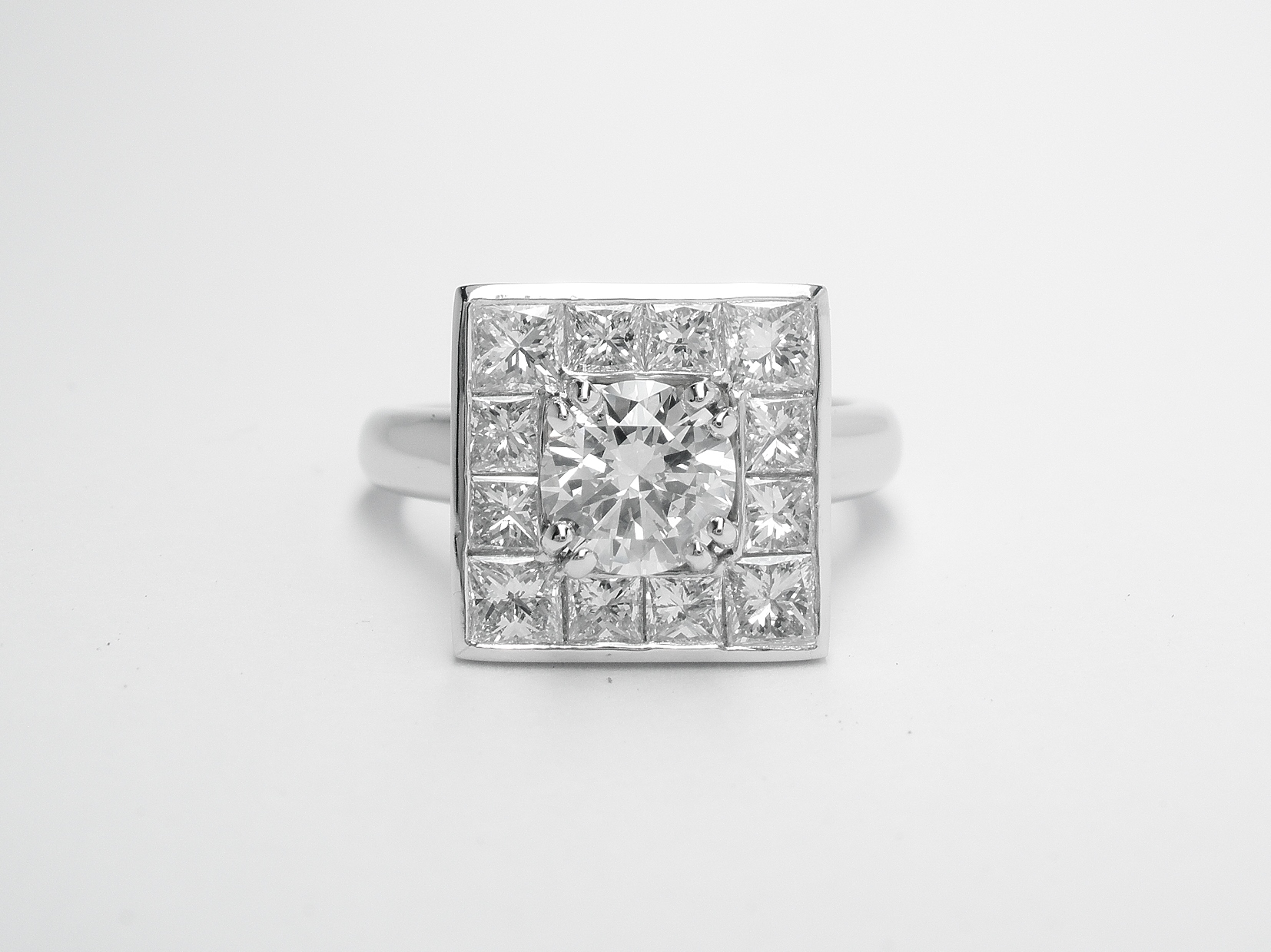 A 13 stone princess cut and round brilliant cut square halo cluster set in platinum.