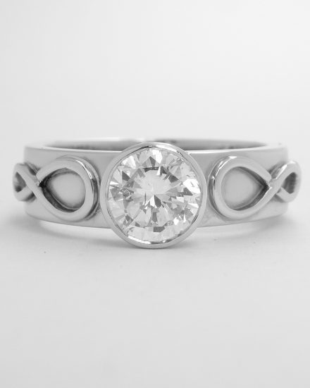 Single rub-over set round brilliant cut diamond ring mounted in platinum with Celtic motif overlay on shoulders.