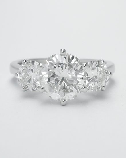 A 3 stone round brilliant cut diamond ring mounted in platinum with large raised centre diamond.