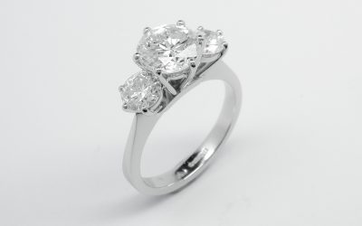 A 3 stone round brilliant cut diamond ring mounted in platinum with large raised centre diamond.