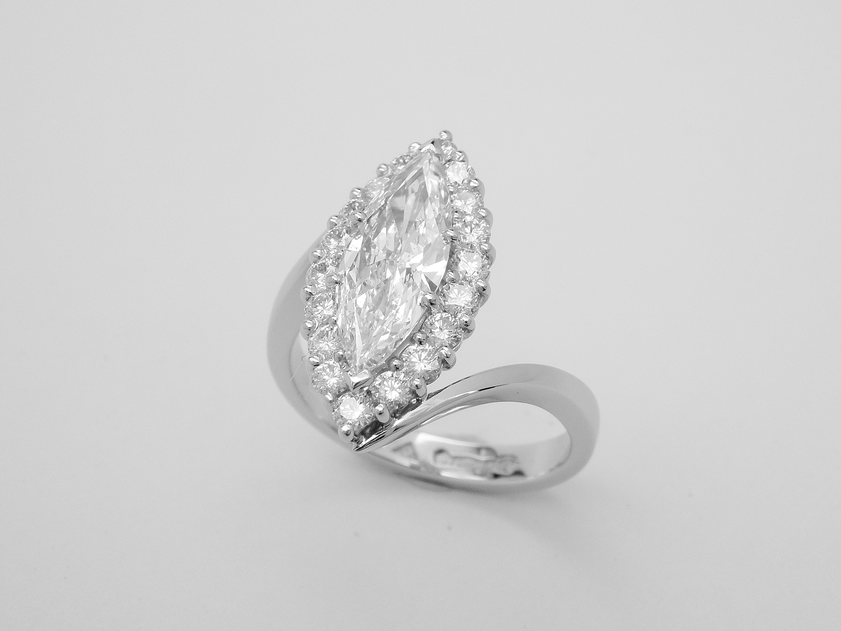 A marquise diamond and round brilliant cut diamond cross-over style ring mounted in platinum.