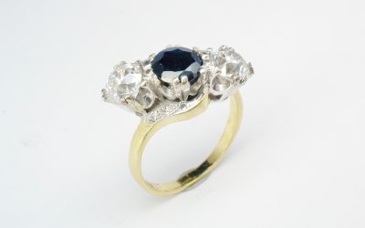 A 3 stone cross-over diamond and sapphire ring mounted in an 18ct. white gold block style setting with an 18ct. yellow shank set with small diamond set in the shoulders.