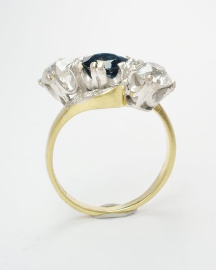 A 3 stone cross-over diamond and sapphire ring mounted in an 18ct. white gold block style setting with an 18ct. yellow shank set with small diamond set in the shoulders.