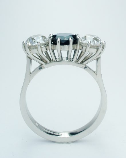 3 stone sapphire & diamond peg set ring mounted in platinum with small diamond channel set in the shoulders.
