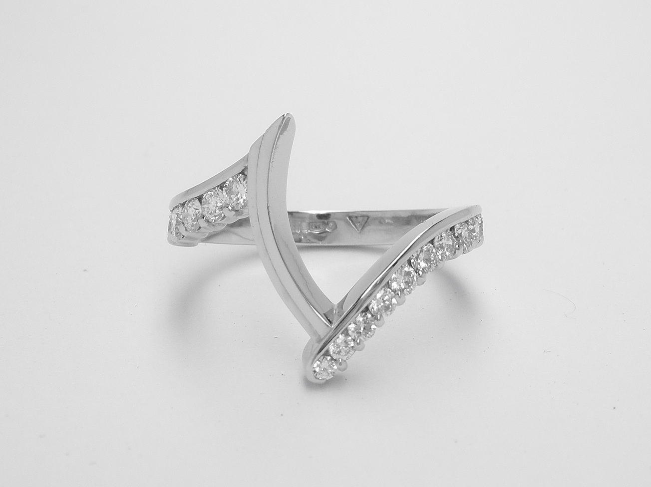 A platinum 15 stone part channel set wedding ring shaped to fit around a marquise shaped diamond cluster cross-over engagement ring.