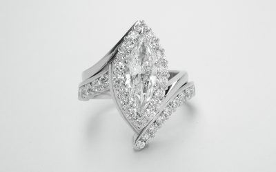 A platinum 15 stone part channel set wedding ring shaped to fit around a marquise shaped diamond cluster cross-over engagement ring.