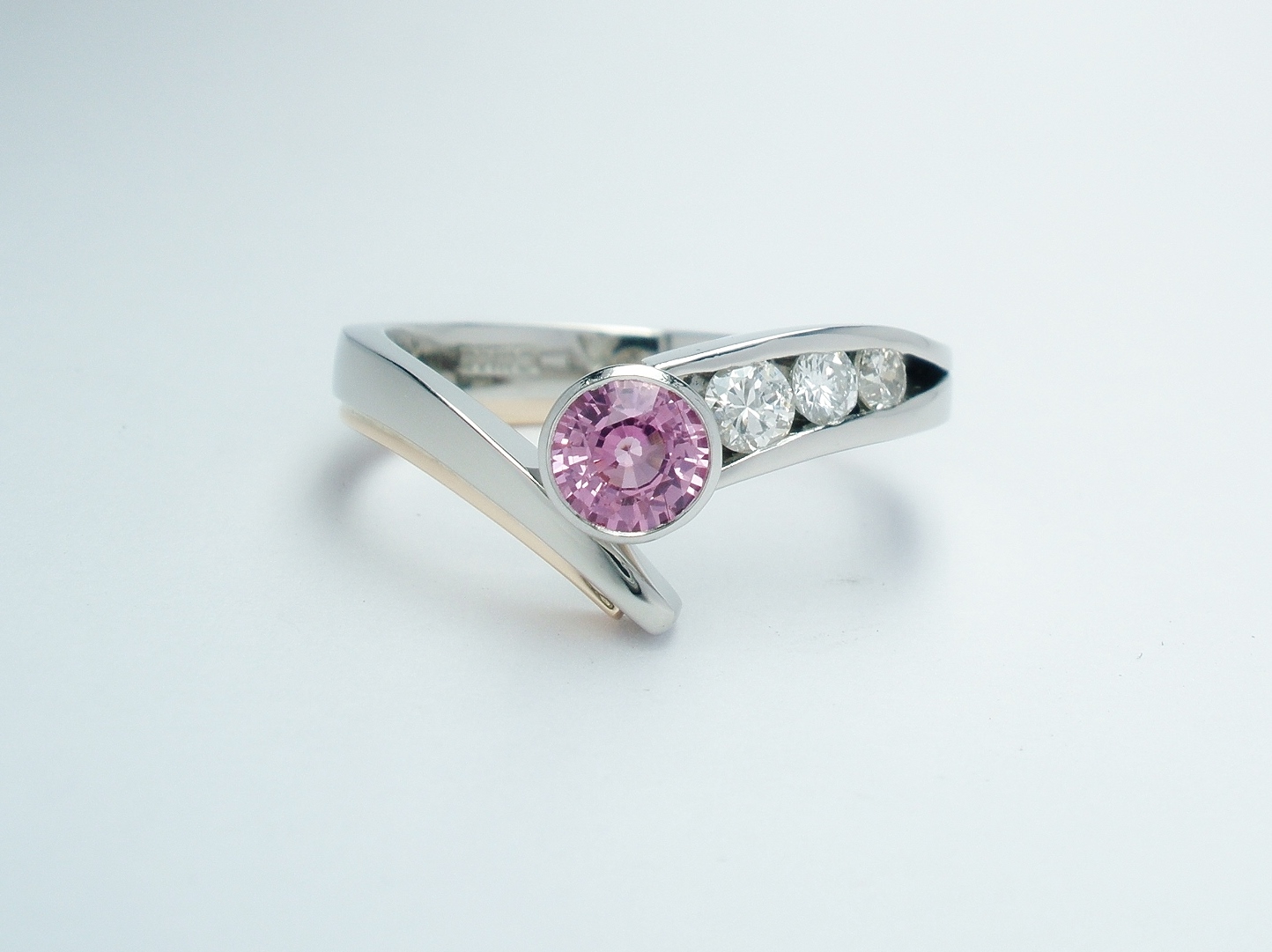 A round pink sapphire and diamond 4 stone ring mounted in palladium, platinum & 9ct red gold.
